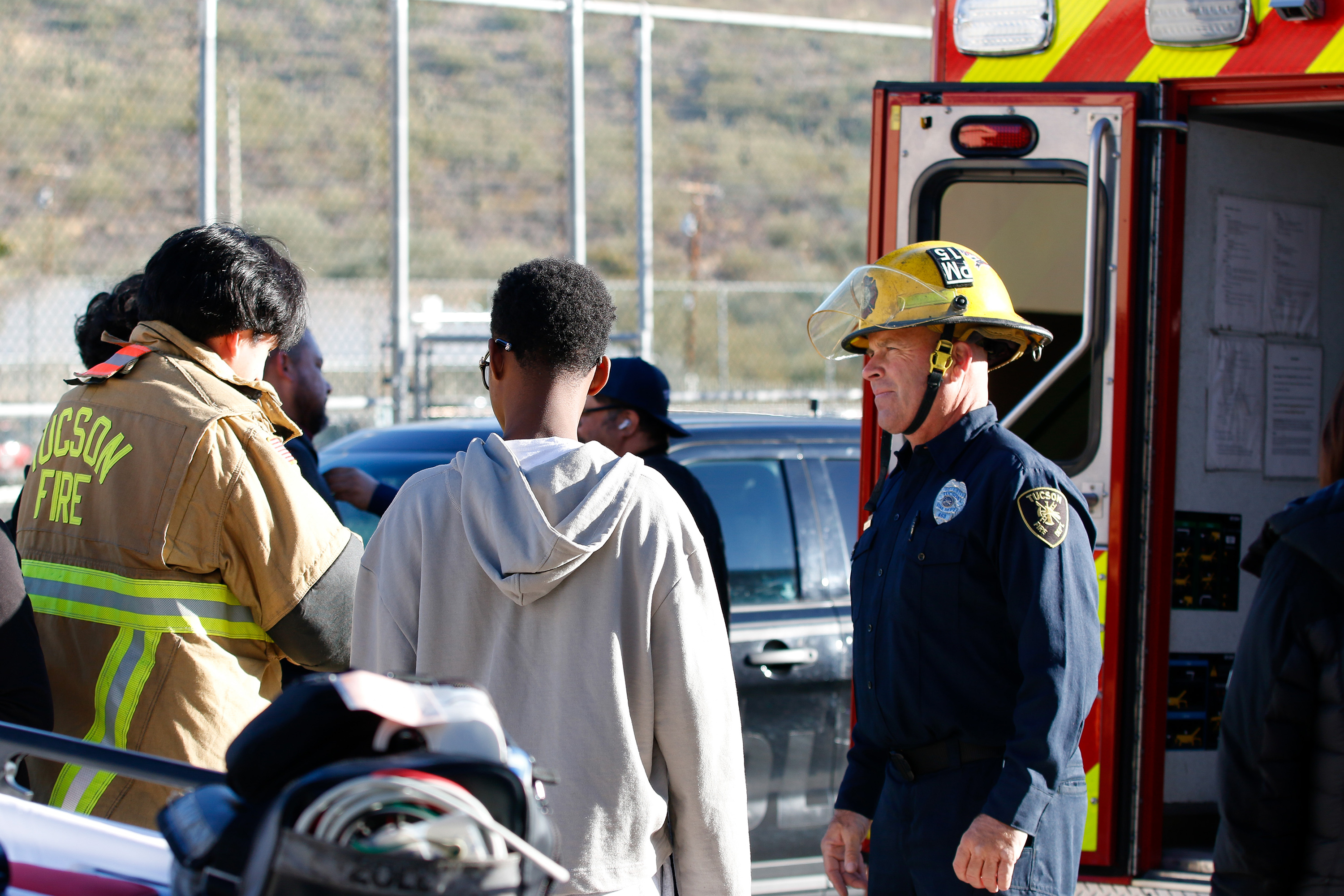 A firefighter stands outside the fire engine with students gathered around