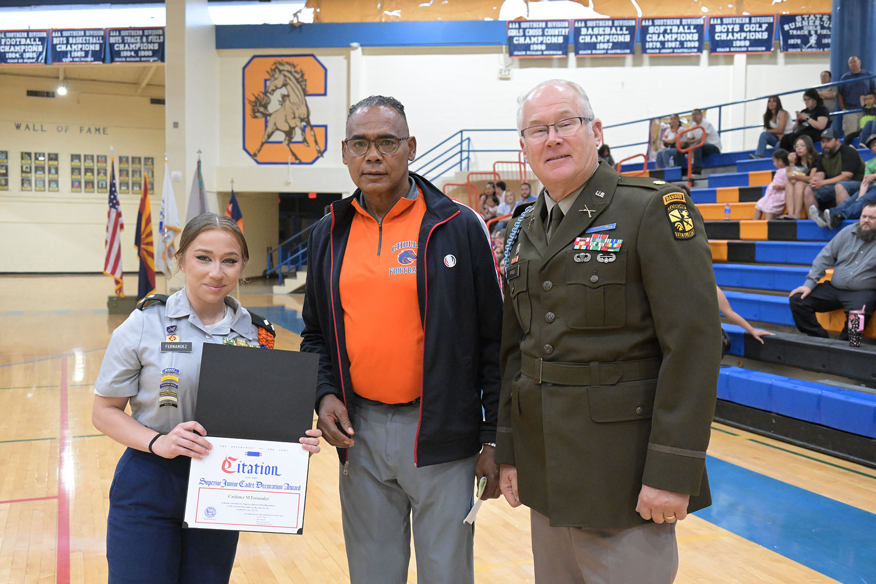 A teen girl holds up her plaque next to two men