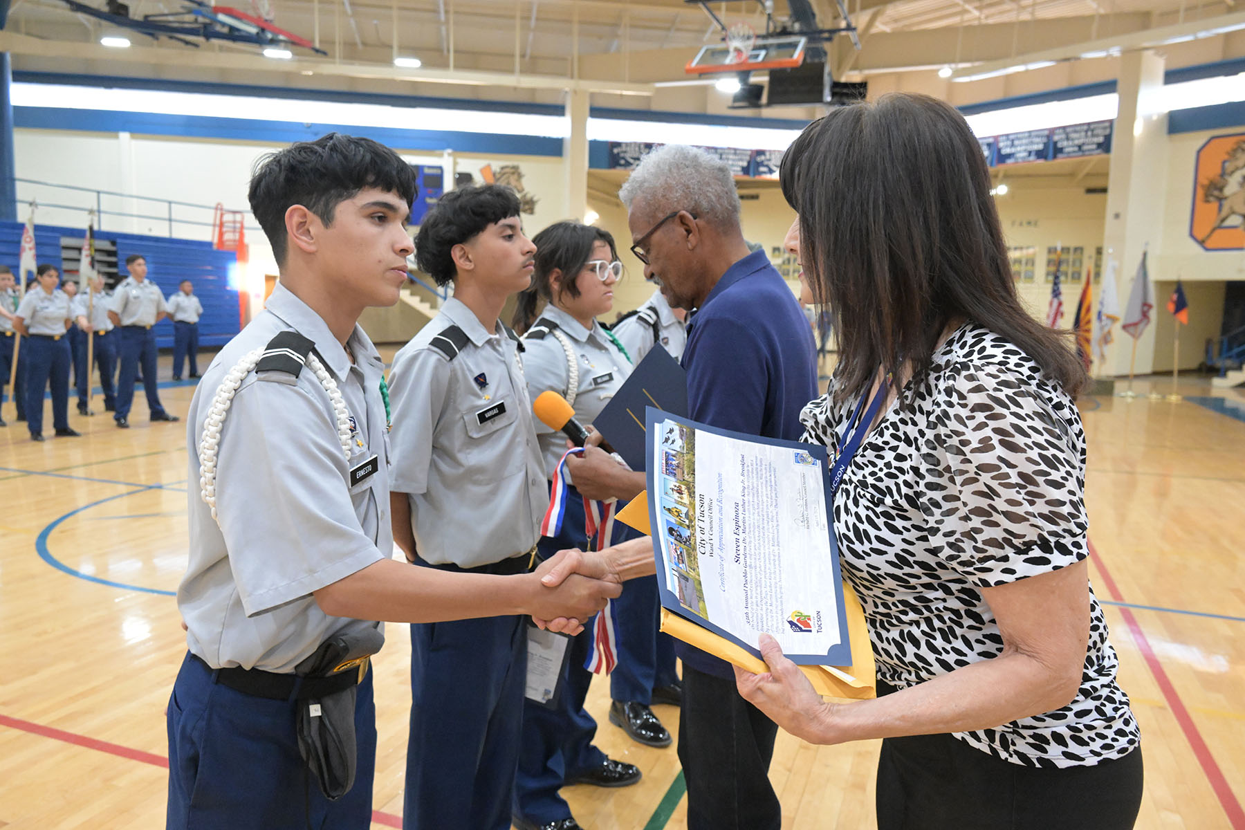 A teen boy shakes a woman's hand as he gets his plaque
