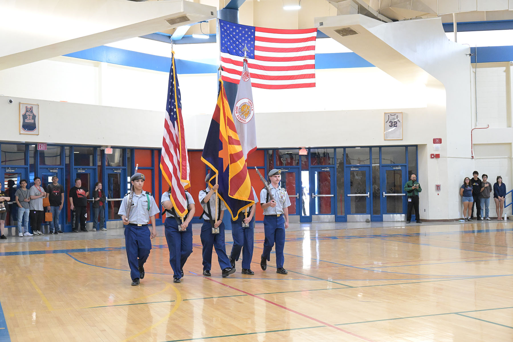 A group of cadets walk with the American and Arizona flags