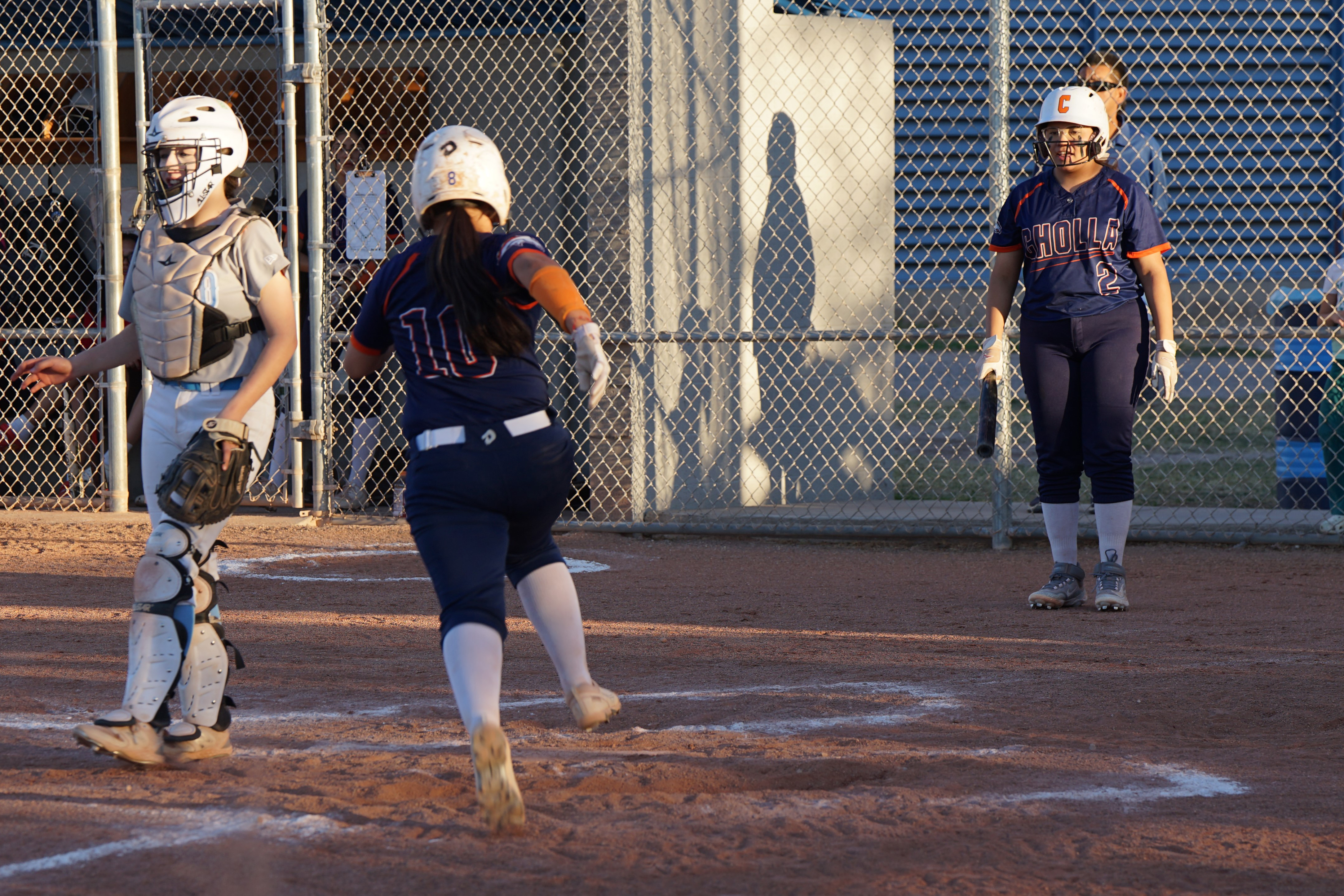 A softball player rounds the corner to home plate