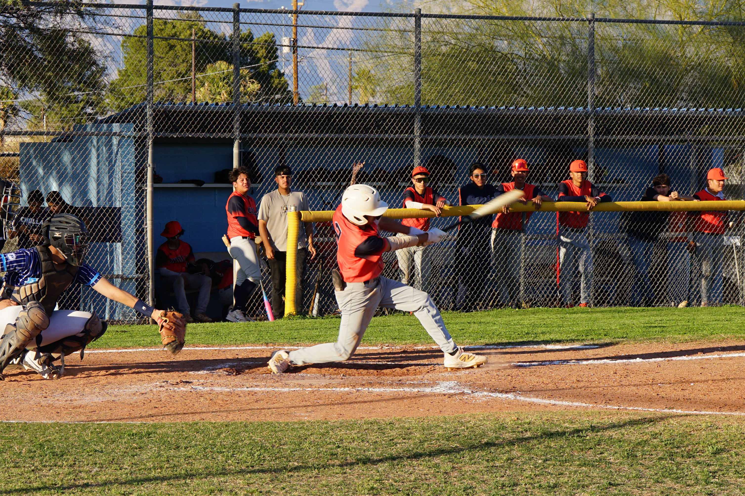 A baseball player swings the bat at the ball