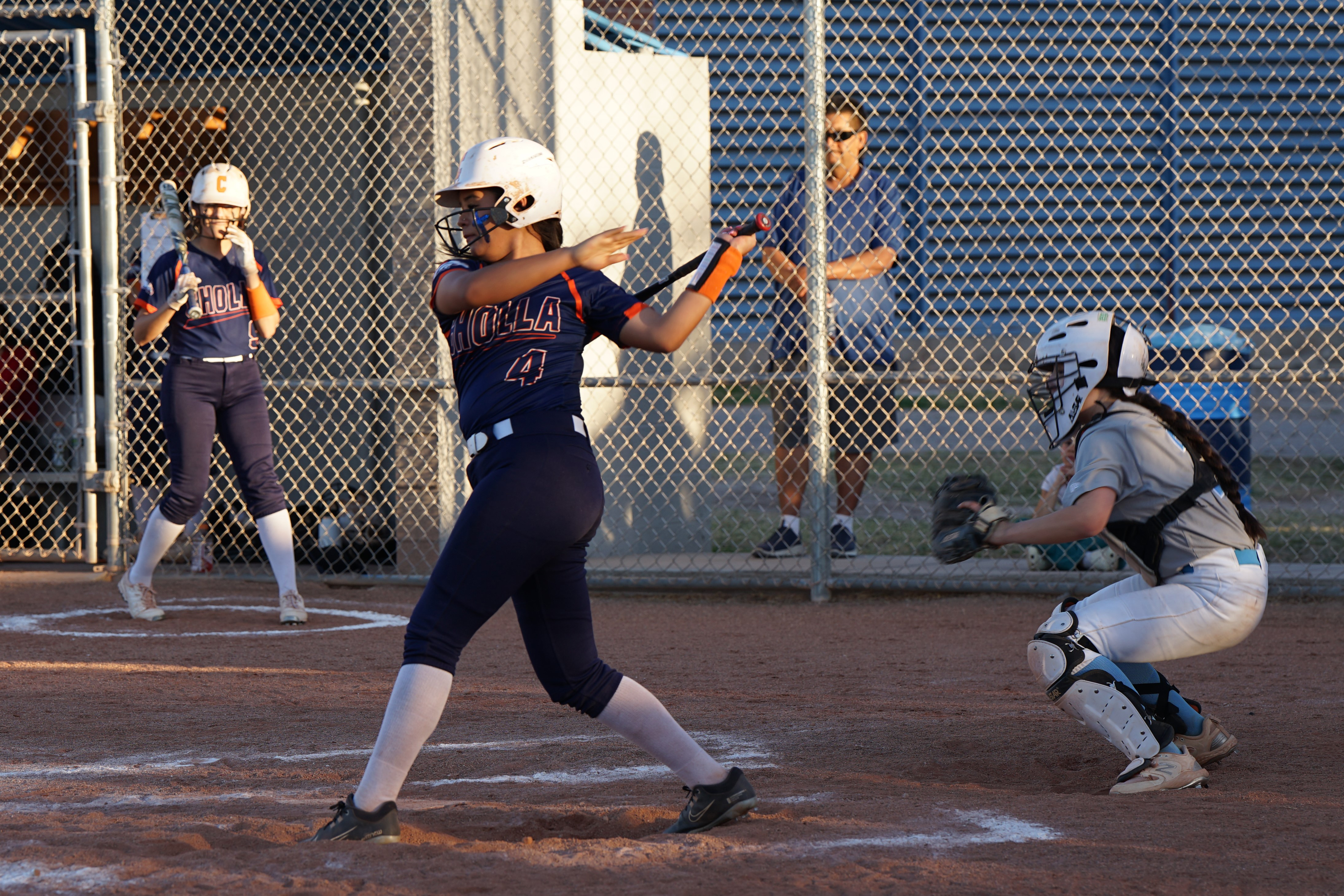 A softball player swings her bat