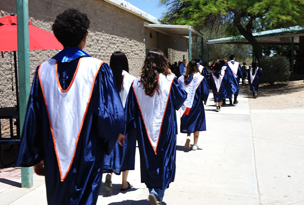 Students walk into a school in their graduation gowns