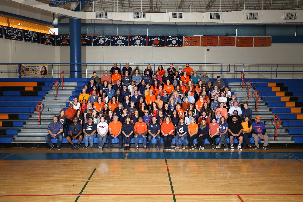 Staff and faculty sit in the bleachers