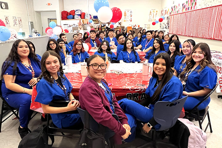 A group of sports med students smile at a table decorated with balloons