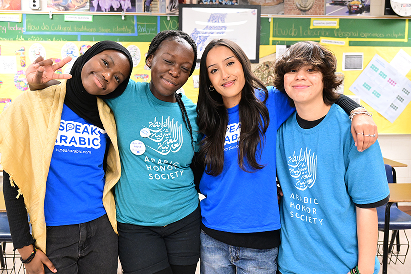 Four students in Arabic program shirts smile for a group photo
