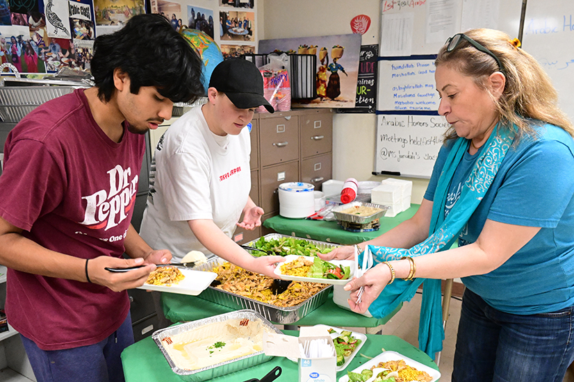 A woman serves traditional Arabic food to students