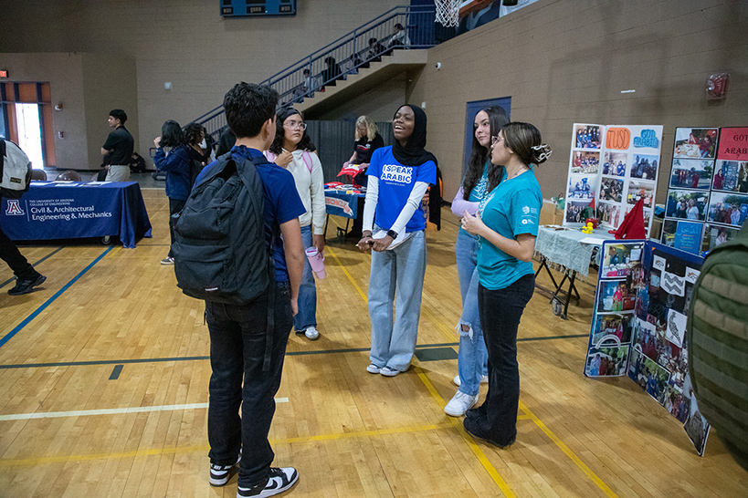 Students stand in a circle in the gym talking