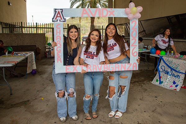 Three teen girls smile in a photo frame for AVID