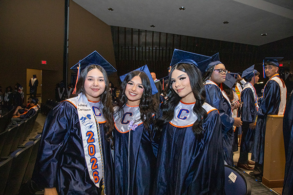Three teen girls pose for a photo in their caps and gowns