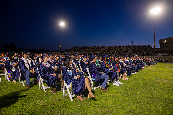 Graduates sit on the field during the ceremony