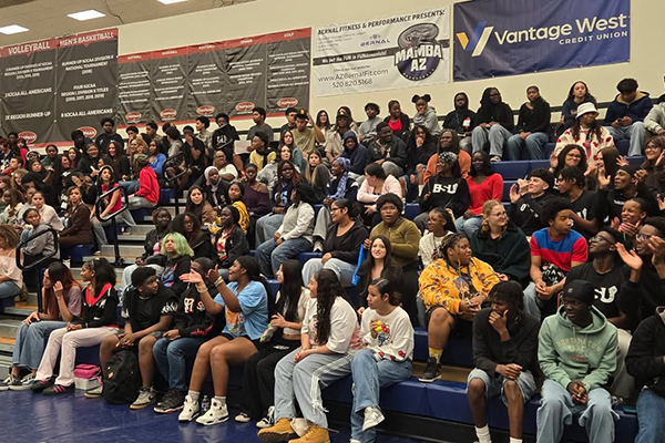 Students sit in bleachers listening to a presentation