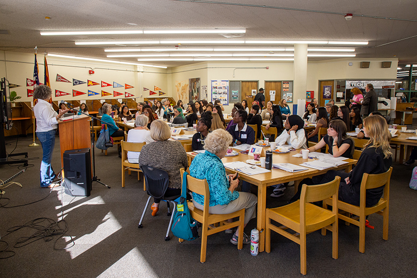 A wide view of the Cholla library, with women and teen girls sitting around tables