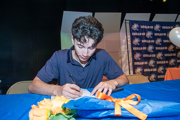 A teen boy signs his college letter of intent