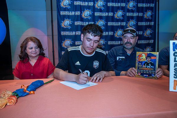 A teen boy signs his college letter of intent