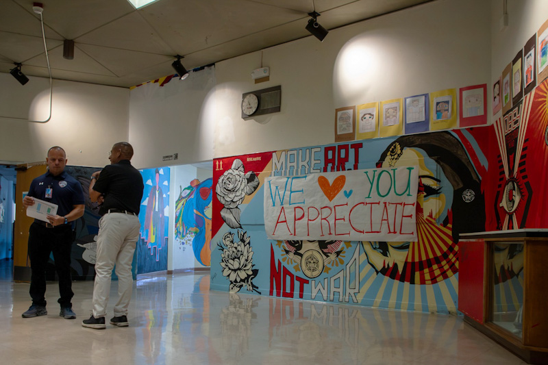 Cholla's principal and Dr. Trujillo chat out in the hallway near some murals
