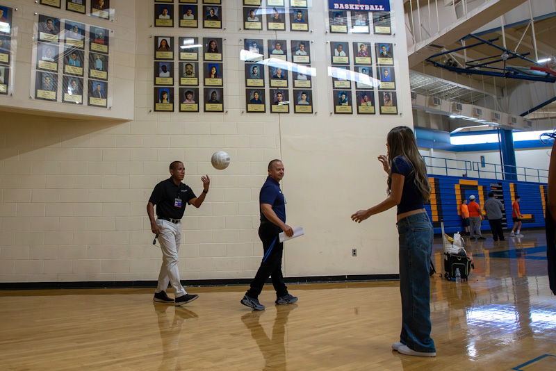 Dr. Trujillo tosses a volleyball to a teen girl in the gym
