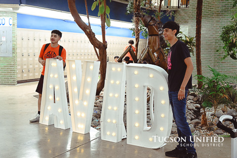 Students stand beside lighted AVID sign.