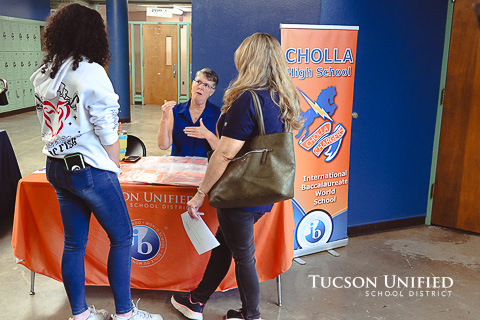 Students listen at the Cholla table while a staff member explains.